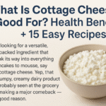 Illustrated graphic with green text reading 'What Is Cottage Cheese Good For? Health Benefits + 15 Easy Recipes' alongside a white bowl of cottage cheese and fresh basil leaves on a beige background.