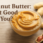 Glass bowl filled with smooth peanut butter, surrounded by whole peanuts, with the text 'Peanut Butter: Is It Good for You?' in bold, dark brown letters above the bowl on a wooden surface.